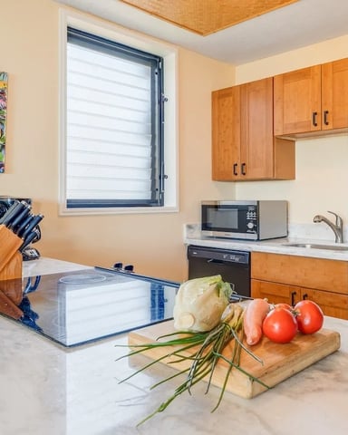 Modern kitchen with wood cabinets, marble countertop, fresh vegetables, and colorful abstract wall art