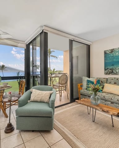 Open-plan living room with ocean and mountain views, dining area, sofa, and sliding glass doors to balcony