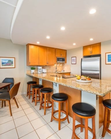 Open-plan kitchen and dining area with orange cabinetry, granite countertop, bar seating, and dining table