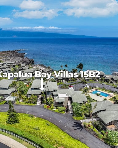 Aerial view of Kapalua Bay Villas resort with modern homes, palm trees, ocean, and West Maui mountains in distance