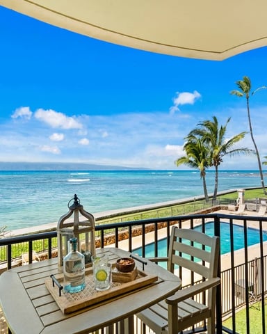 Beachfront balcony with ocean view, palm trees, lounge chairs, and turquoise water