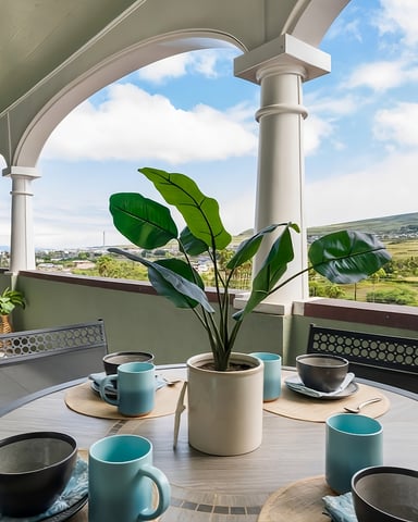 Covered rooftop terrace with dining table, potted plant, tea service, and panoramic valley views under arched columns