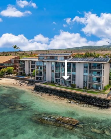 Beachfront condominium building with solar panels overlooking turquoise ocean and sandy beach, tropical landscape beyond